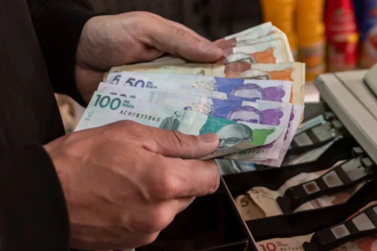 Fotografía de manos contando billetes de Colombia.